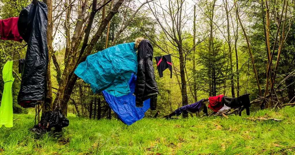 wet clothes and sheets are drying in the forest on tourist camp