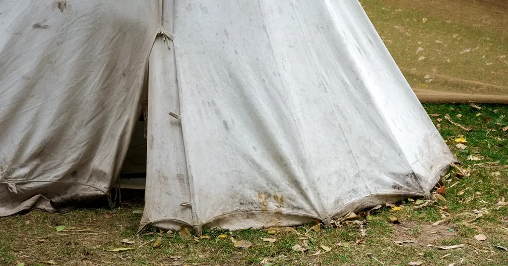 Detail of dirty canvas tent standing on grass