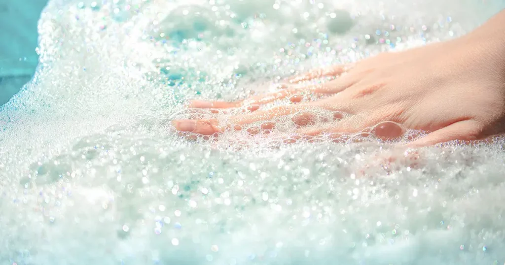 hand in foam, airy soapy foam on the water, take a bath with foam, wash clothes