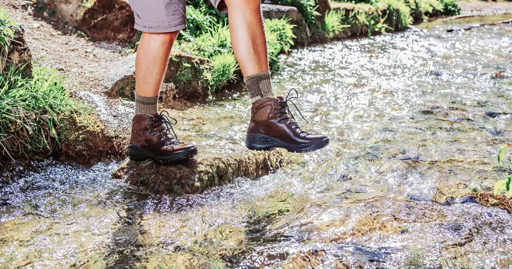 Male legs, in waterproof sports hiking boots, walking on water