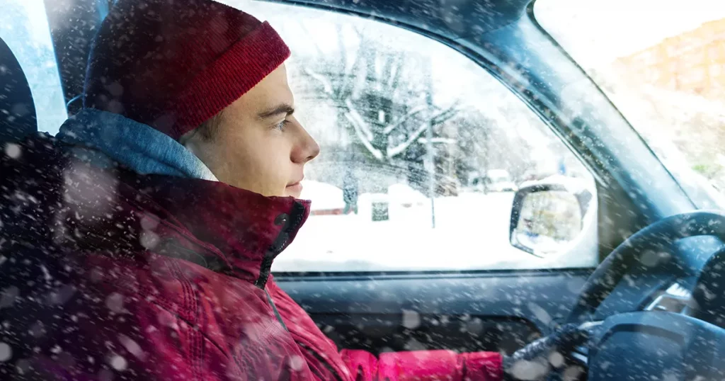 A man in winter clothes drives a car in winter
