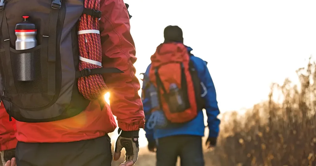 Rear view of male backpackers walking in field