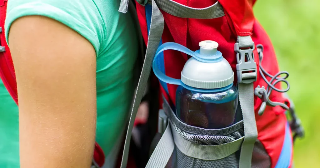 travel, tourism, hike and people concept - close up of woman with water bottle in backpack pocket