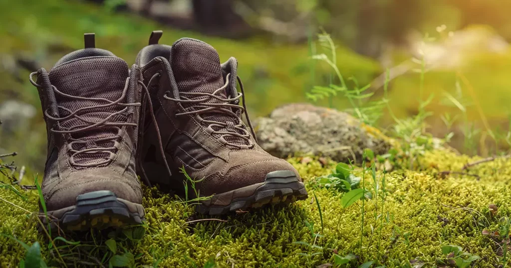 Pair of touristic boots on moss in forest