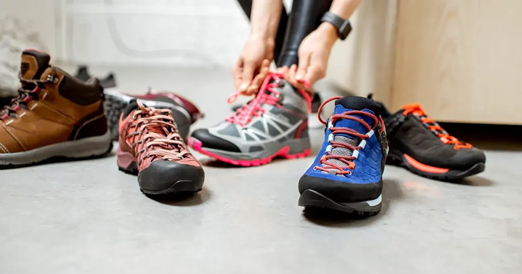 Woman trying different trail shoes for mountain hiking in the sports shop, close-up view with no face