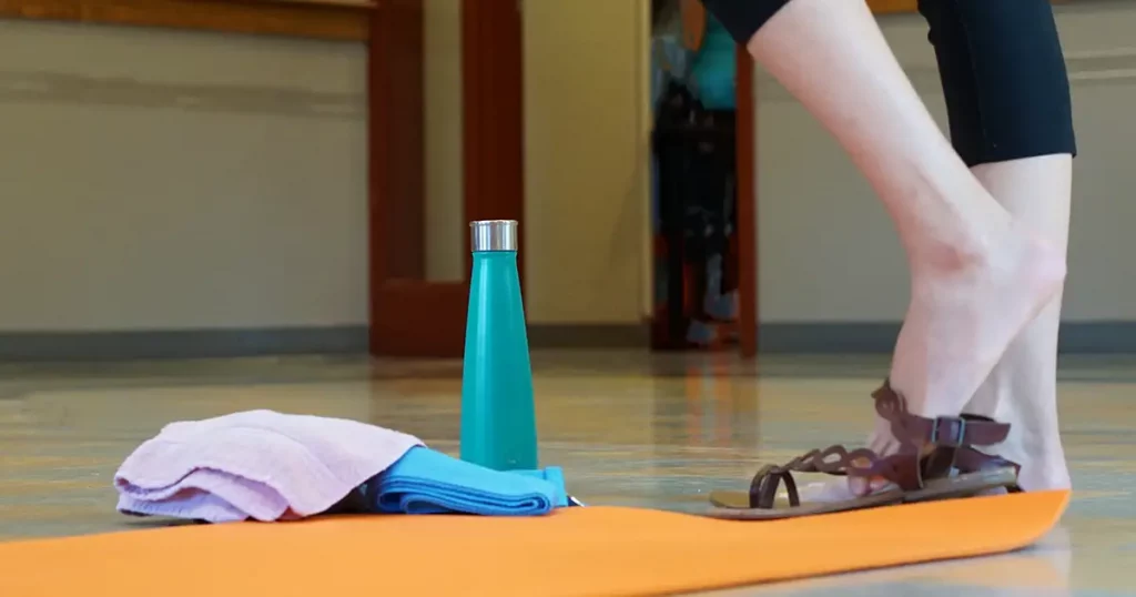 Woman Taking Off Her Shoes To Do Yoga