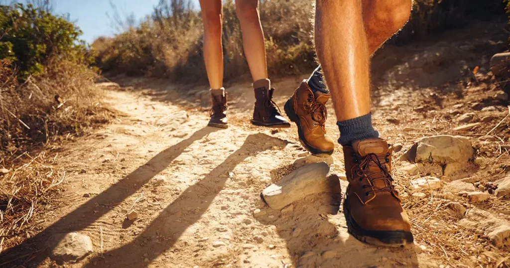 Close-up of legs of young hikers walking on the country path