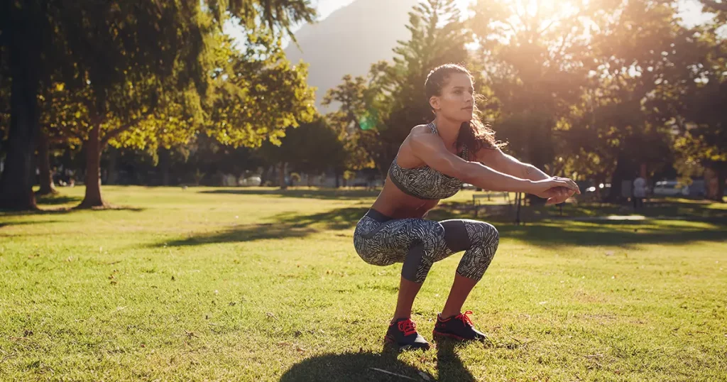 Full length shot of young woman practicing squats in park