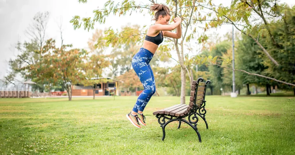Young woman jumping in public park, exercising.