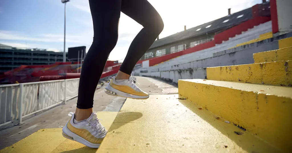 cropped image of female legs running up the concrete staircase. side view