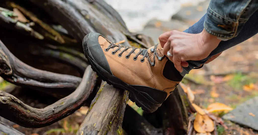woman tying hiking boot outdoors on trail in fall