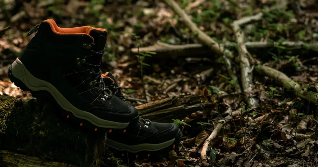 Closeup on pair of dark grey hiking boots on a natural raw wood in the woodland