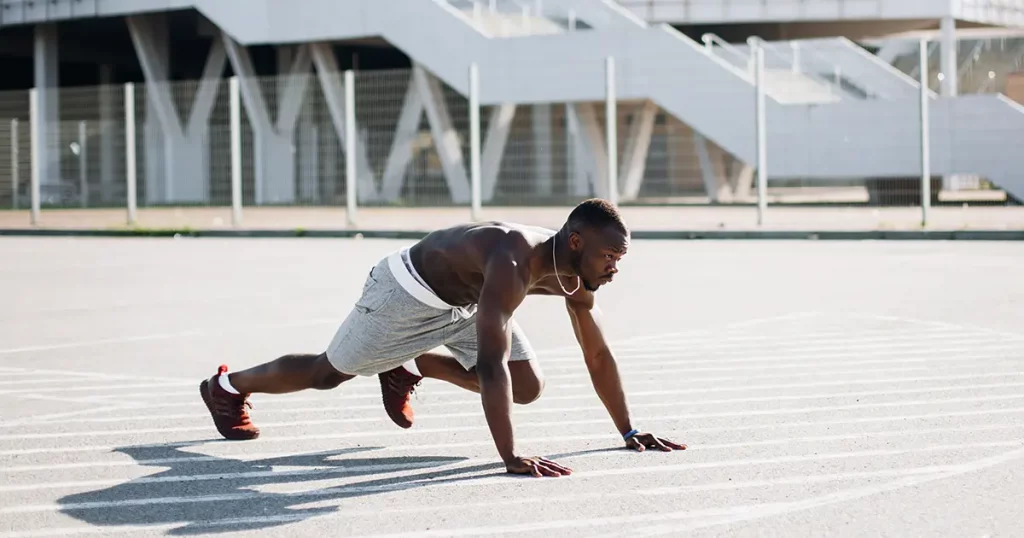 Attractive African American man does burpees working out on the street