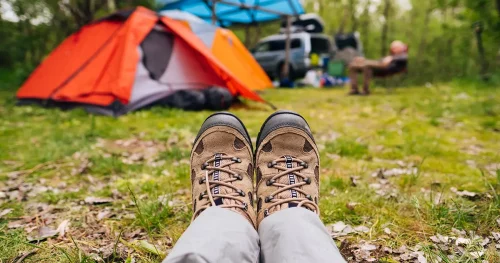 Traveler hiking boots near camping tent outdoors