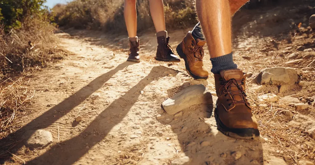 Close-up of legs of young hikers walking on the country pat