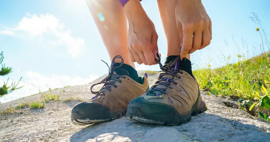 Hiking shoes - woman tying shoe laces. Closeup of female tourist getting ready for hiking