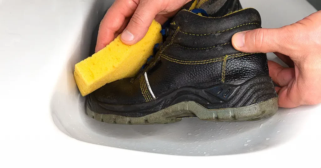 a black boots is in a white sink washed with a yellow sponge