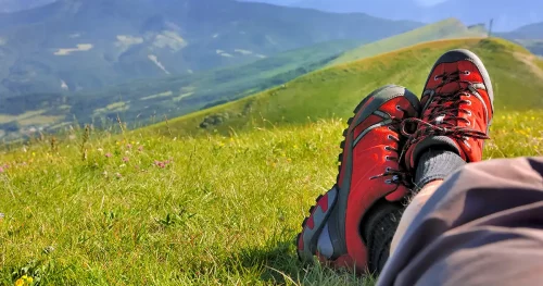 red shoes walking an lying hiker front of a mountainous landscape
