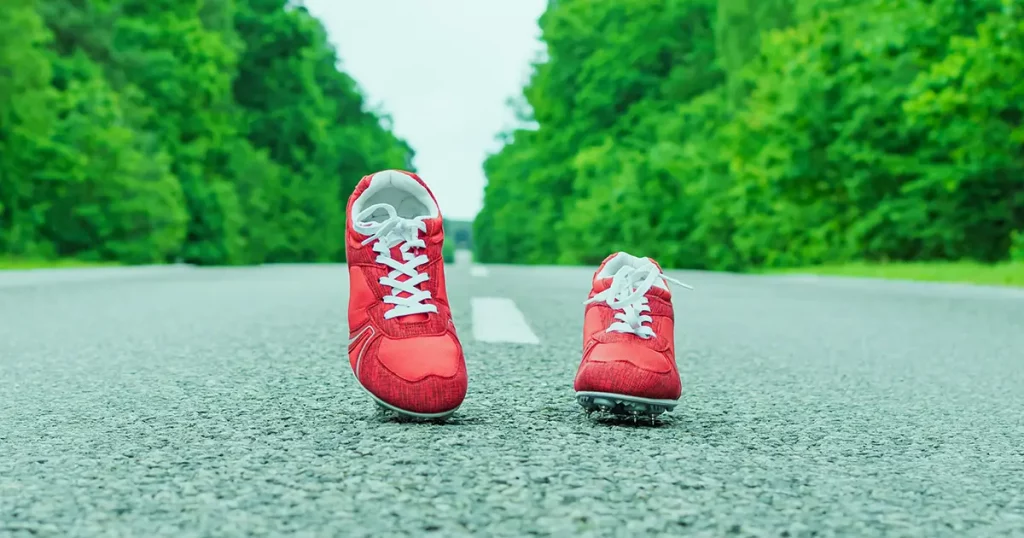 Sports boots with red spikes are on the road