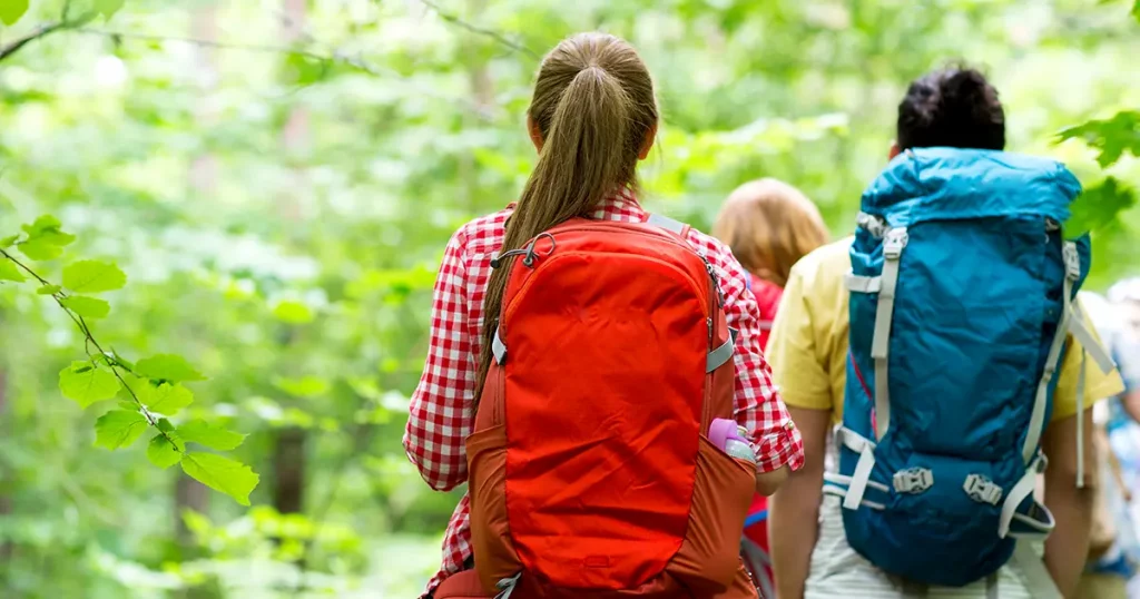 close up of friends with backpacks hiking