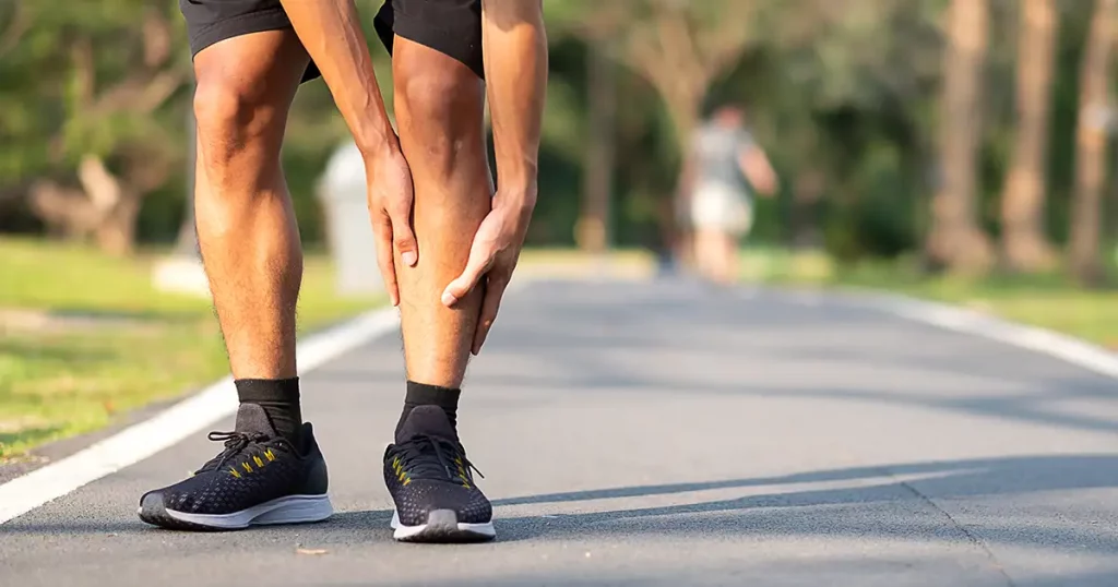 Young fitness man holding his sports leg injury. muscle painful during training