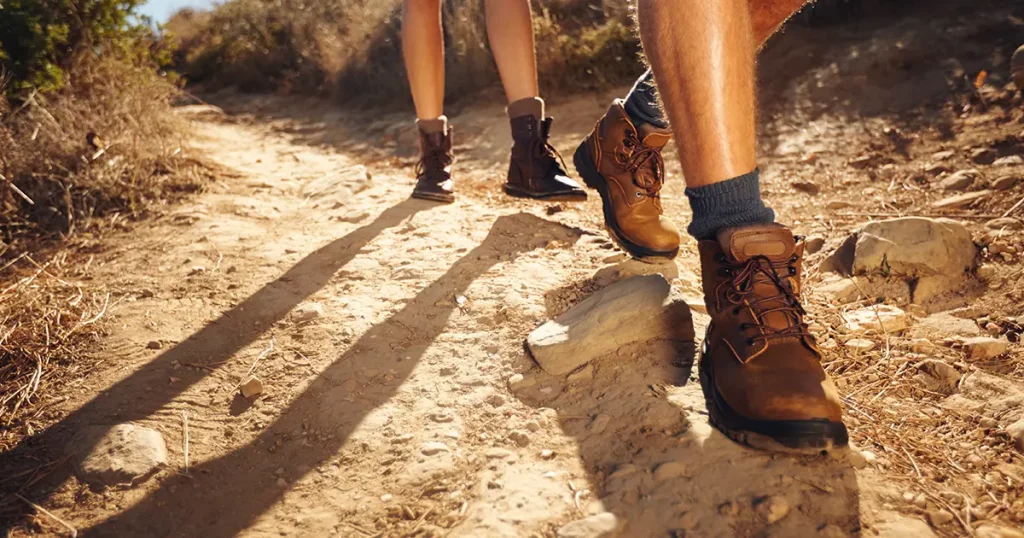 Close-up of legs of young hikers walking on the country path