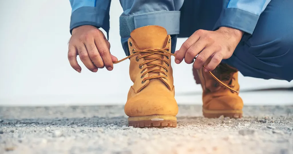 Man kneel down and tie shoes industry boots for worker