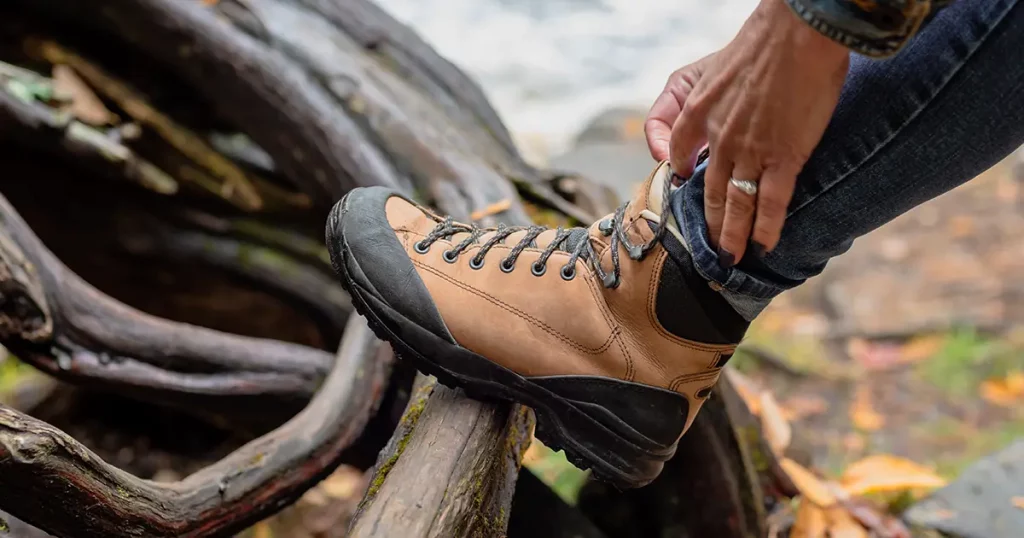 woman tying hiking boot outdoors on trail in fall