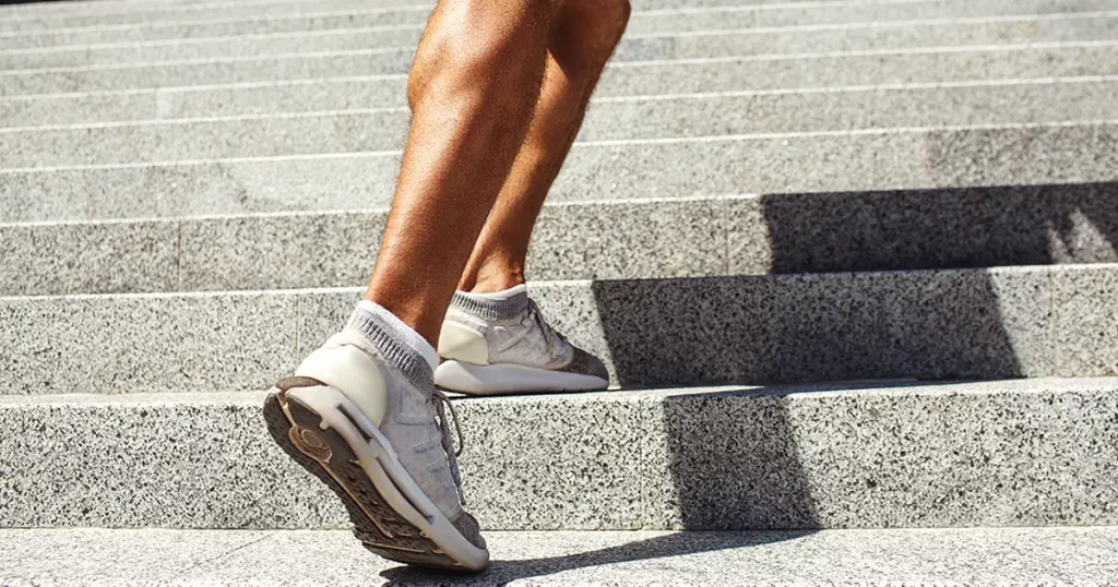 Young man exercising outside. Cut view of strong powerful legs and feet in sneakers. Muscled calf