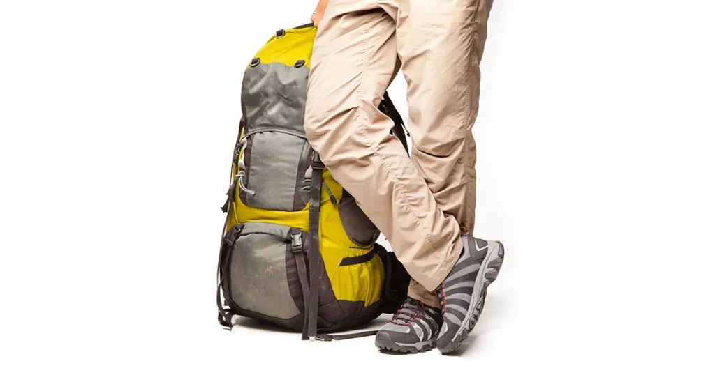 Man stands near packed backpack and ready to go