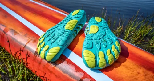 lightweight low-profile water shoes (soles up) for kayaking and other wet sports on a deck of a stand up paddleboard