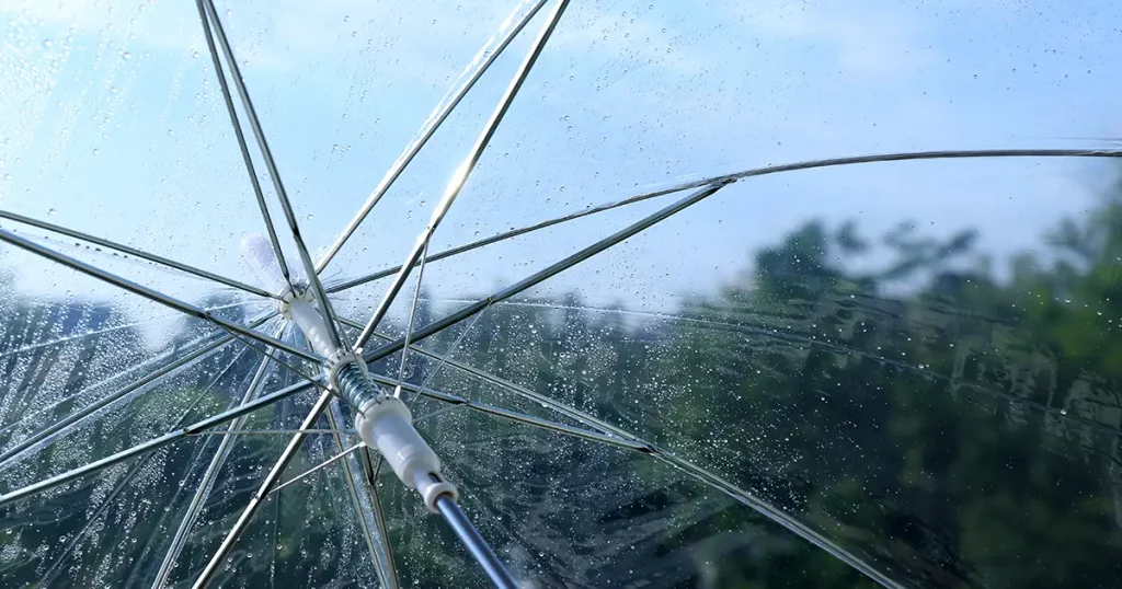 Wet transparent umbrella on sky background