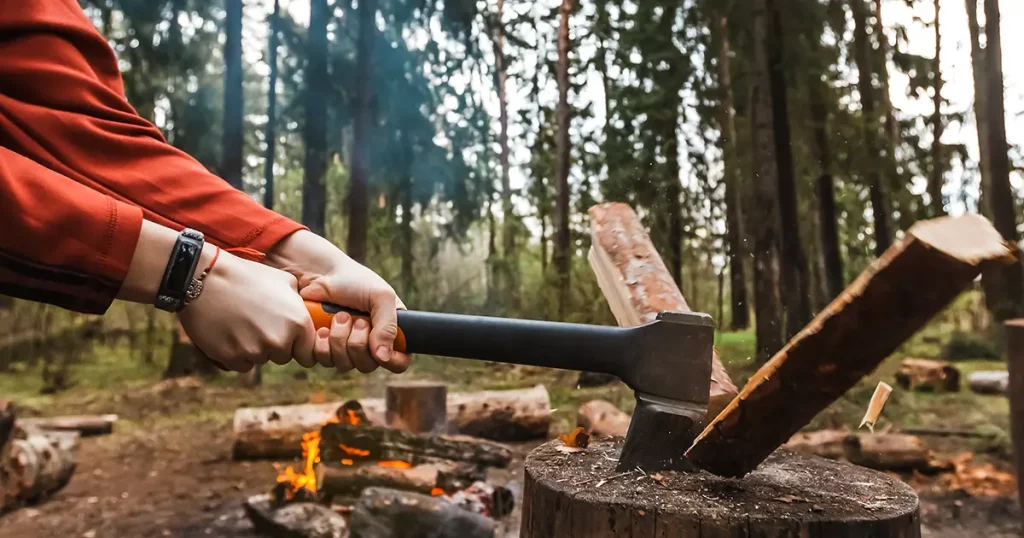 strong hands chop firewood with axe for bonfire