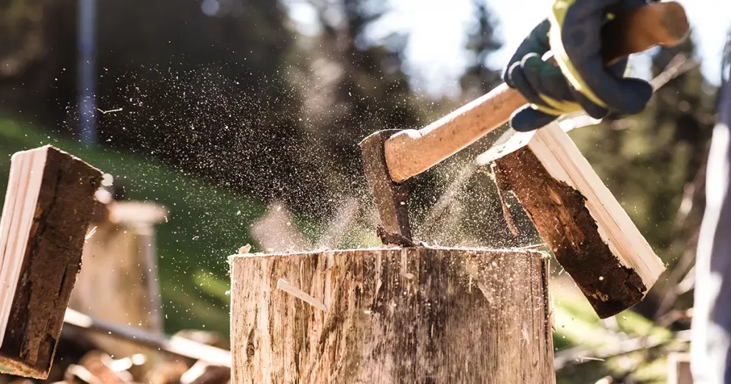 Detail of two flying pieces of wood on log with sawdust. Man is chopping wood with vintage axe