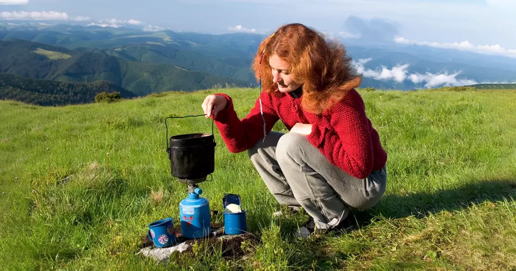 Girl making a coffee in a mountains on gas burner