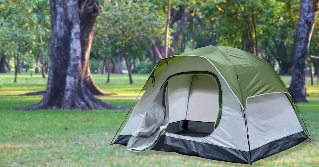 Open medium size tourist tent on blurred campsite in forest location