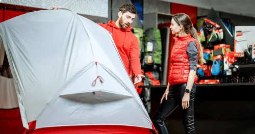 Salesman selling camping equipment to a young woman client in the sport shop