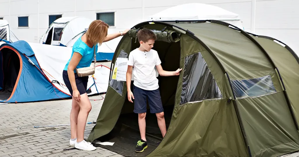Woman and boy choose a camping tent in the store