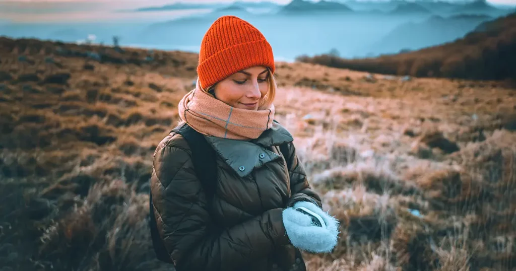 Woman holding in hands portable electric hand warmer, winter gadget for keeping hands warm