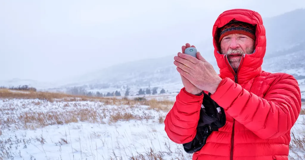 cold senior male hiker with a pocket electric hand warmer