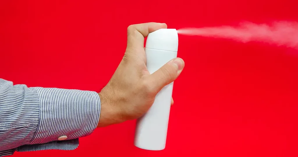 spray being pulverized from a white can by a business man's hand