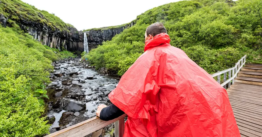 tourist man standing in red poncho closeup on bridge