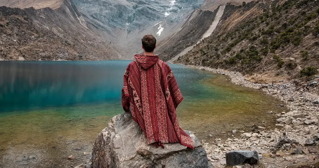 A young man with a poncho on vacation in Laguna Humantay, Peru