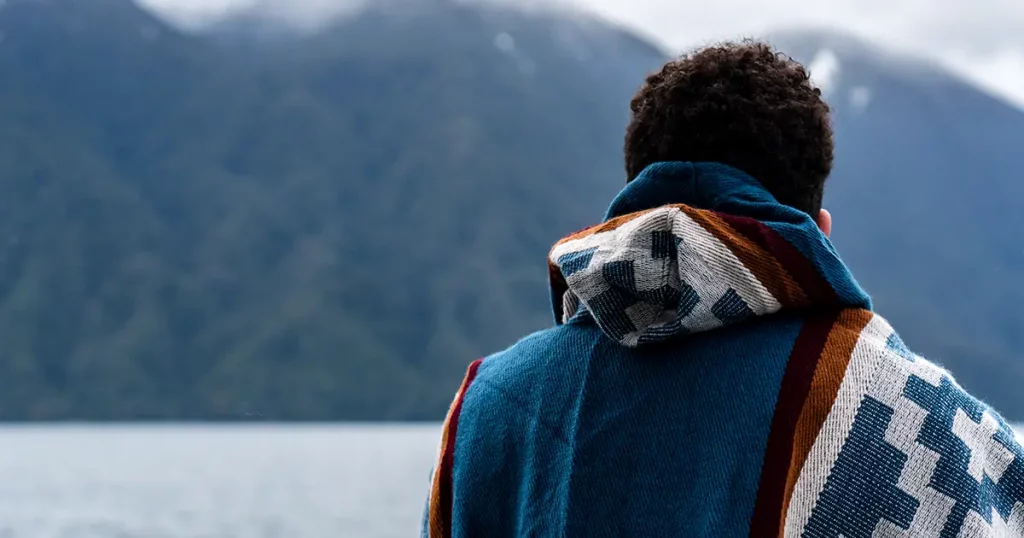 Young man wearing a blue poncho on a cloudy day on his trip to Peulla.