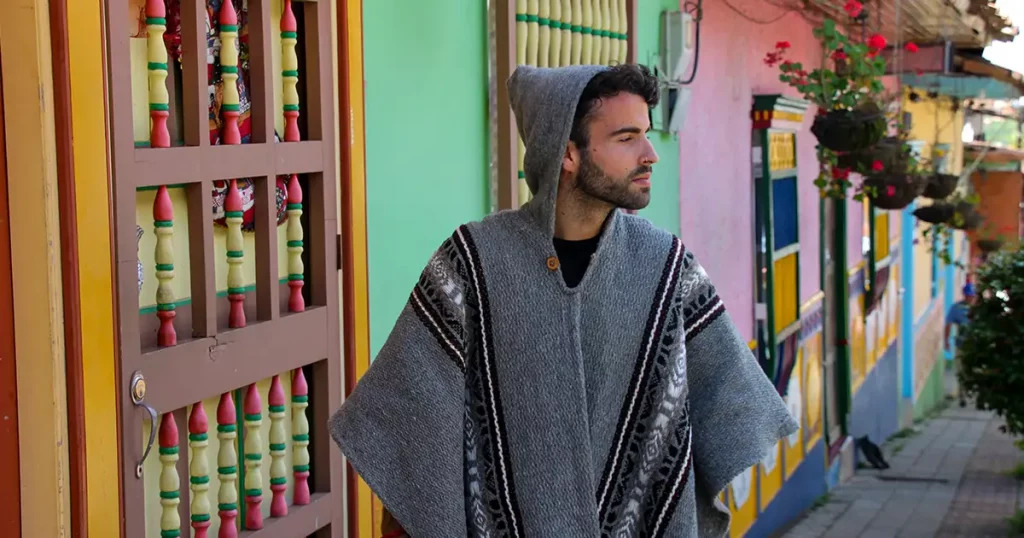 Man with poncho walking on a colorful main street, Marinilla