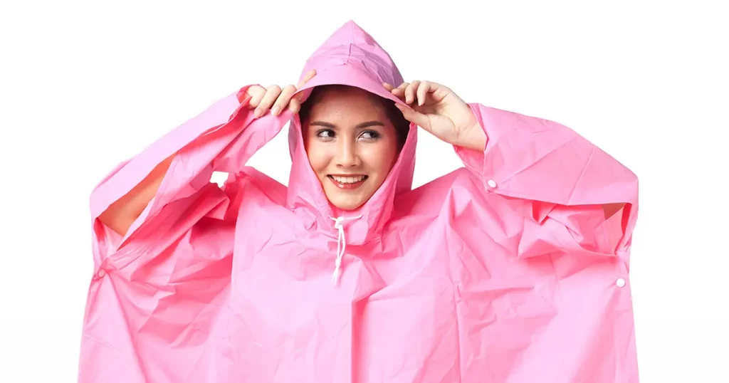 beautiful woman wear pink raincoat, arms holding hood. Isolated white background.