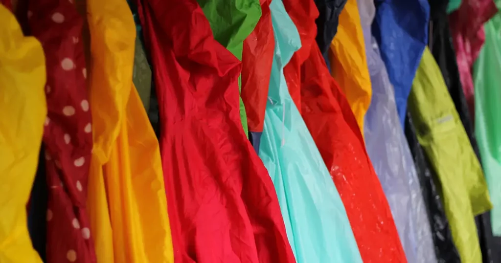Many wet children's raincoats of different colors are hanging on hangers to get dry again