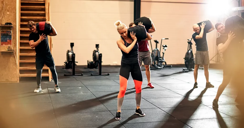 Fit group of people working out with weight bags during a strengthening class in a gym