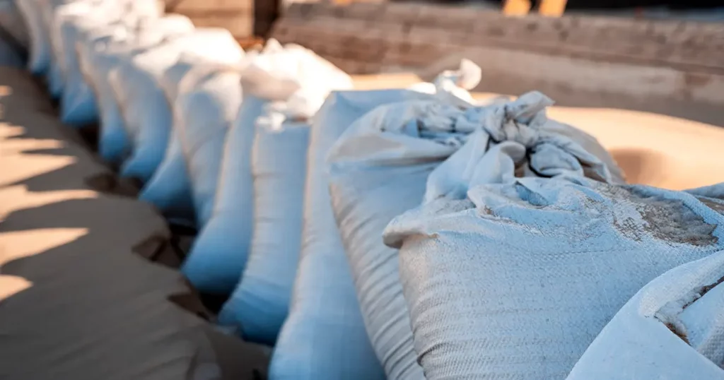 White sacks with building material on the beach sand