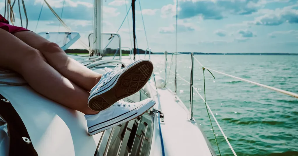 view on legs of relaxed young woman sunbathing on a sailing yacht during sailing
